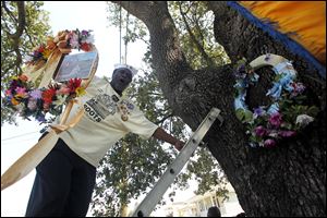Lower 9th Ward resident Robert Green, who lost his mother and niece in Hurricane Katrina, replaces a wreath from last year with a new one, at the spot his home landed after the flooding, commemorating the sixth anniversary of Hurricane Katrina in New Orleans, Monday, Aug. 29, 2011.