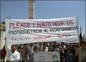 In this citizen journalism image made on a mobile phone and provided by Shaam News Network, Anti-Syrian President Bashar Assad protesters, hold up a banner pleading for help from Nato, during a demonstration against the Syrian regime, at Maaret Harma village, in Edlib province, Syria, on Friday Aug. 26, 2011. Syrian security forces killed at least two people as tens of thousands of anti-government protesters flooded the streets on the last Friday of the holy month of Ramadan, a time that many activists hoped would become a turning point in the uprising.