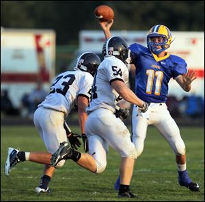 Lake defenders Tim Lohmann (23) and Zach Sharpe (54) puts pressure on Northwood quarterback Nick Russell.