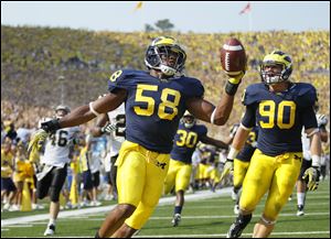 Michigan's Brandon Herron (58) scores a touchdown after intercepting the ball tipped by teammate Jake Ryan (90) in the second quarter against Western Michigan.
