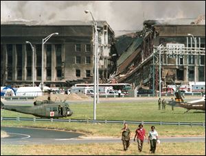 Three rescue workers walk away from the crash site at the Pentagon in Arlington, Va., in this Sept. 11, 2001, file photo.
