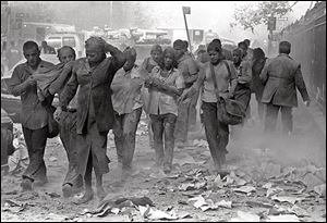 People covered in dust walk over debris near the World Trade Center in New York in this Sept. 11, 2001, file photo.