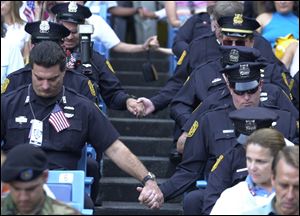 Members of the New York Police Department pray as they hold hands across the aisle at Yankee Stadium on Sept. 23, 2001, at the interfaith  memorial service in honor of the victims of the Sept. 11th attack on the World Trade Center.