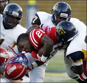 St. Francis tailback Jarrod Jefferson (20) loses his helmet on a hard collision with Whitmer defenders Mark Meyers (17) and Garrett Clarke (21) Saturday, at the Glass Bowl in Toledo.