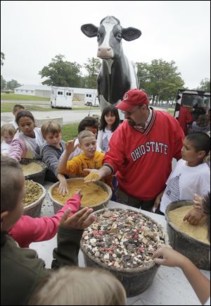 Dairy farmer Clark Emmons, Fayette, shows students different types of food his cows eat during Ag Fest.