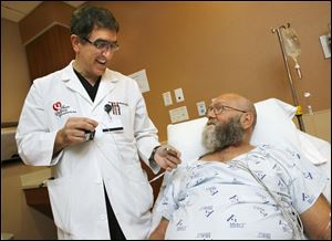 Dr. Ameer Kabour shows John Ward, 63, of Toledo, a sample of the first AngelMed Guardian cardiac monitor that will be implanted in Mr. Ward’s chest.
