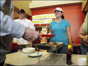 Lisa Walton of Ottawa Lake prepares to serve chicken wings to a diner at the soup kitchen. The day's free meal also included tuna casserole and green beans.