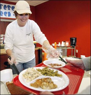 Luann Takats serves a meal to a diner at Crossroads Community Church. The God Works soup kitchen program for which she volunteers serves 1,000 people a week at 14 churches in the Monroe area.