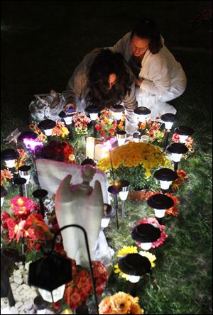 Maytee Vasquez-Clarke, left, is comforted by her sister-in-law Jennifer Rodriquez during a family vigil at the gravesite of Johnny Clarke, Thursday, Sept. 22, 2011.