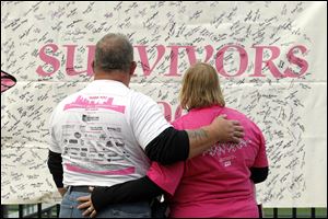 Ron Hawkins and his wife, Yvonne, of Perrysburg, search for names on a survivor banner during the race. Ms. Hawkins, in the race’s signature pink Sunday, is an 11-year breast-cancer survivor.