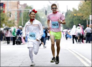 Albert Liu, left, and Ethan Miller wear fun hats as they warm up for the annual Komen Race for the Cure. Many of the participants Sunday wore offbeat garb including pink tutus and witches’ hats.