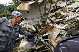 A Nepalese rescue worker inspects the wreckage of the Beechcraft 1900D operated by Buddha Air. The plane hit the roof of a house in a village and broke apart.