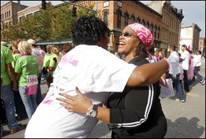 Stephanie Lincoln, left, hugs her friend Yolanda Willis as she runs by during the Komen Northwest Ohio Race for the Cure in downtown Toledo. The head scarf was in keeping with the color of the day.