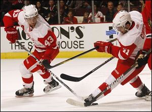 The Red Wings' Chris Conner, right, has the puck under his skate while teammate Darren Helm, left, looks on against the Chicago Blackhawk.