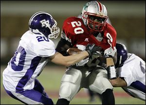 Central Catholic running back Amir Edwards (20) is stopped by Fremont Ross defenders Michael Egbert (20) and Jordan Garcia (23) Friday, 09/30/11, in Toledo, Ohio.