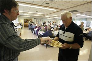 Tim Doerfler, of Riga, left, serves Lawrence Marks, of Palmyra, a roll. 