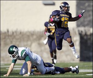 University of Toledo player Eric Page hurdles Eastern Michigan University punter Jay Karutz, 37, as he returns the punt for a touchdown in the second quarter at the Glass Bowl, Saturday.