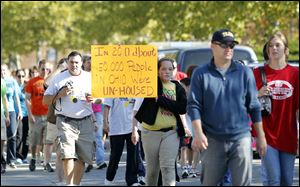 Haley Haase, 16, carries a sign in the 1 Mile Matters Walk. The mile-long walk, which drew many young people Sunday, went through the south end of downtown.