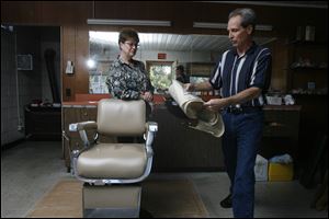 Gail Hauser-Hurley watches from behind the chair as her husband, Ron Hurley, brings memorabilia out of storage at the Razor's Edge, the shop he opened in 1978. 