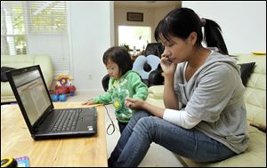 Sherry Zheng, with daughter Kaylin, 2, speaks with a person in the office of U.S. Rep. Marcy Kaptur (D-Toledo) from her Holland, Ohio, home Thursday. Her husband,  Wei Zheng, has been held by U.S. Immigration in a jail near Cleveland and is facing deportation to China because he lied to a judge in 1995 about his entry in to the United States.