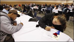 Michael Johnson and Maria Bofia, both of Toledo, fill out employment applications at the job fair. The event downtown was sponsored by The Source, the county commissioners, and U.S. Rep. Marcy Kaptur (D., Toledo).