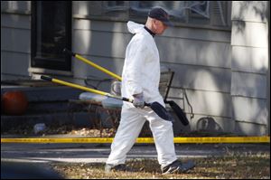 An investigator carries shovels to the back yard of missing baby Lisa Irwin in Kansas City, Mo., Wednesday.