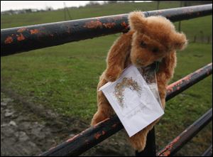 A stuffed animal with a sympathy card attached hangs from the locked gate at the Muskingum County Animal Farm Thursday in Zanesville, Ohio.