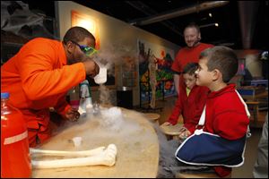 Jason Pope sets the mood for all things Halloween by creating smoke for 9-year-old Findlay brothers Ben, wearing a sling, and Nate Garcia. Watching the experiment with dry ice was their uncle, Jim Price of Pittsburgh. 
