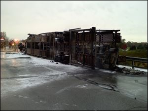The charred remains of a car hauler rests on its side in the westbound lanes of the Ohio Turnpike just east of the Albon Road overpass.