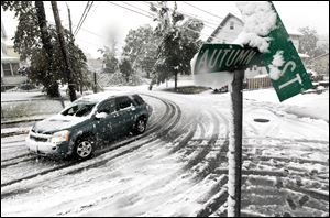 A vehicle makes its way at the snow-covered intersection of Autumn and Grove Streets in Lodi, N.J., following a rare October snowstorm that hit the region, Saturday.