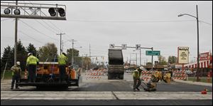 Pavement is installed as part of the rail reconstruction on Dorr Street. The work should allow, by late this year or early next year, bigger trains to pull in or out without delaying other trains on Norfolk Southern’s main line through Toledo.