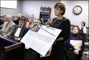 Theresa Sullivan, vice president of the Tiffin Historic Trust, presents a mock-up of an advertisement to be placed in the local newspaper that would include the names of 400 people who support saving the courthouse. 