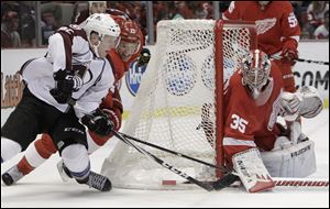 Detroit's Brad Stuart defends against Colorado's Gabriel Landeskog as Wings goalie Jimmy Howard stops a shot.