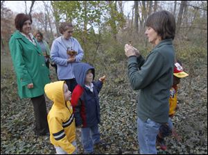 Pam Menchaca, senior naturalist, right,  talks about a leaf while Drake Stearns, 2, front left, and Cole Bradford, 4, front right, from Wayne, Ohio, listen during a Leaf Collection Keepsake event at William Henry Harrison Park.