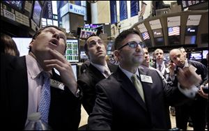 Specialists William Bott, left, Christian Sanfilippo, third from left, and floor official Chris Casaliggi second left, work Thursday on the floor of the New York Stock Exchange.