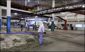 Workers pour concrete in BX Solutions facility at Toledo Express. The renovations are to transform BAX Global, the cargo hub that shut down Sept. 1, to fit the new business geared to trucked freight.
