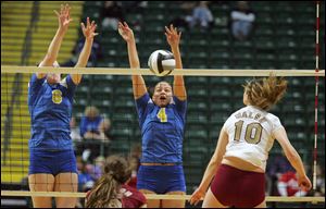 St. Ursula's Erin Williams, 4, puts the block on the shot of Walsh Jesuit's Emma Klein, 10, during the semi-final game of the OHSAA Div. I girls state volleyball tourney played at the Nutter Center in Fairborn, Ohio.