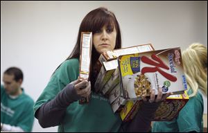 Branch manager Lindsay Reese, has her hands full as she and other volunteers from Charter One sort food at the Northwest Ohio Food Bank as part of the companies Carving Out Hunger Program, Tuesday.
