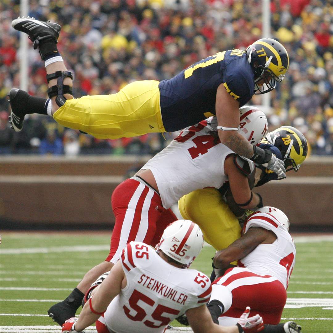 Michigan-s-Taylor-Lewan-leaps-over-a-pile