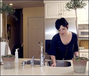 Beth Rogers wipes out the kitchen sink at her home in Fayetteville, Ark. When having visitors for the holidays, experts suggest focusing on tidying the common areas to keep cleaning manageable.