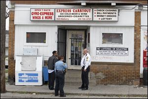 Police stand near the Express Carryout, 1920 Mulberry St. in North Toledo. Authorities say one person has been fatally shot.