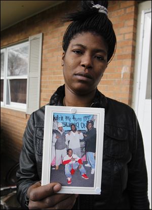 Kenyata Ratliff, one of Allen’s 16 siblings, holds a picture of her brother, seated in the photo. ‘He is gone but he is not forgotten,’ she said.