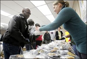 Craig Adams, left, receives dessert from volunteer Paige O'Loughlin at the MLK Kitchen for the Poor.
