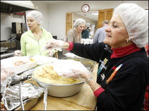 Taylor Holloway, left, and Mary Lou Leonard, foreground,  help dish up about 200 servings of turkey with all the fixings and other Thanksgiving fare at the Kitchen for the Poor's holiday feast Wednesday. 