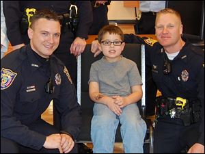 Perrysburg Township officers David Molter, left, and Joe Ball, right, were among those who helped Bryce Johnson, 5, center, get new glasses from Walmart after he was in a car wreck caused by another passenger.