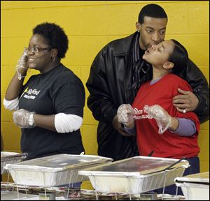 Justin Jones, center, gives Ashley Jones, right, a Thanksgiving greeting while Lyn-sey Bishop, left, serves on the buffet line during the first annual Thanksgiving Dinner at the Rhema Word Christian Fellowship.