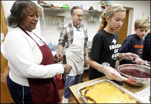 Henrietta Armstrong, left, head cook at the MLK Kitchen for the Poor, and Jim Bishop watch as volunteers Mary Bishop, 14, and Patrick Bishop, 12, help serve food at the kitchen's annual Thanksgiving meal. 