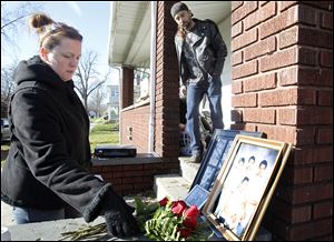 Christina Mahs, a friend of Veronica Serrano's since childhood, puts red roses in front of family pictures.