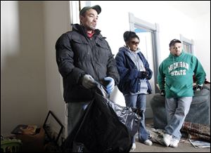 Henry Serrano, left, Tina Serrano, and family friend Tim Caldwell pause while clearing what's left of the belongings.