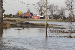 The River Raisin floods a section of Iffland Road just north of Blissfield, Mich.